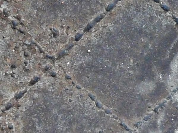 Aged metal tread texture in dark brown tones with uneven grid texture and worn, rusting surface.